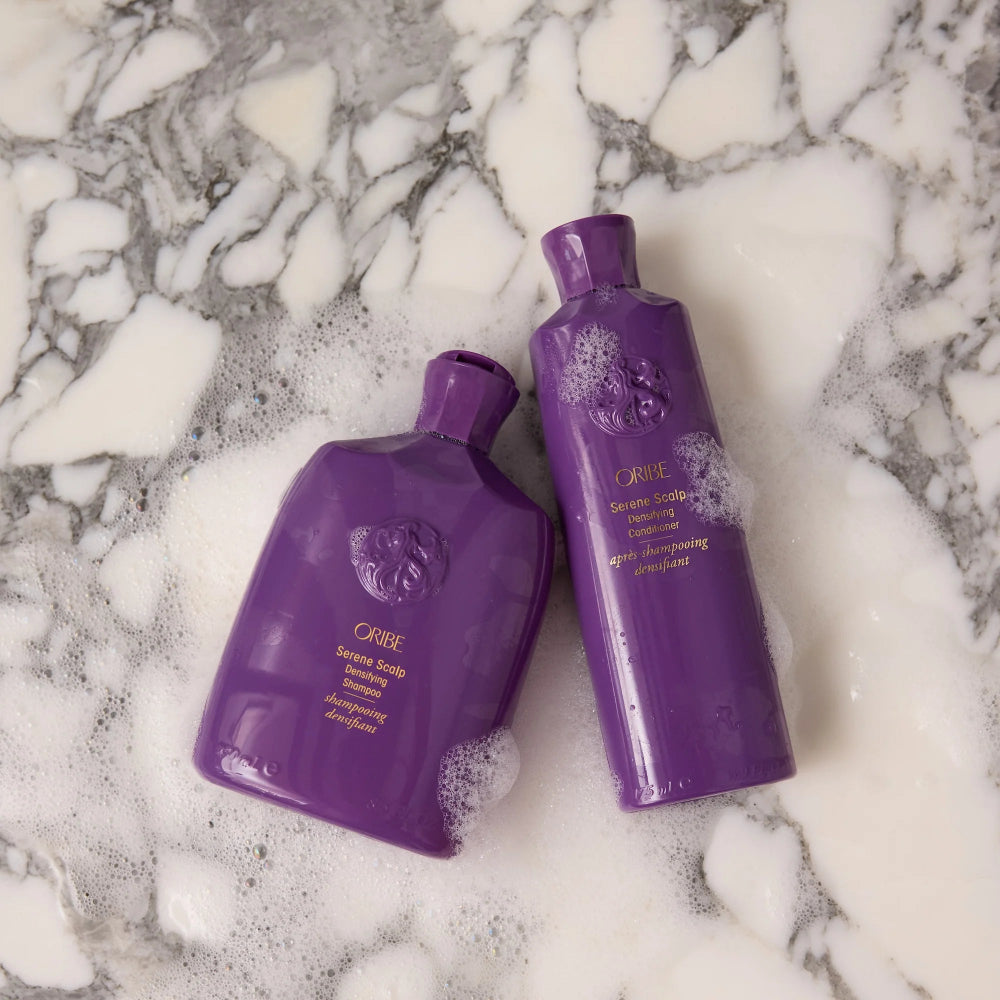 Oribe Serene Scalp Densifying shampoo and treatment displayed on marble for luxury hair care