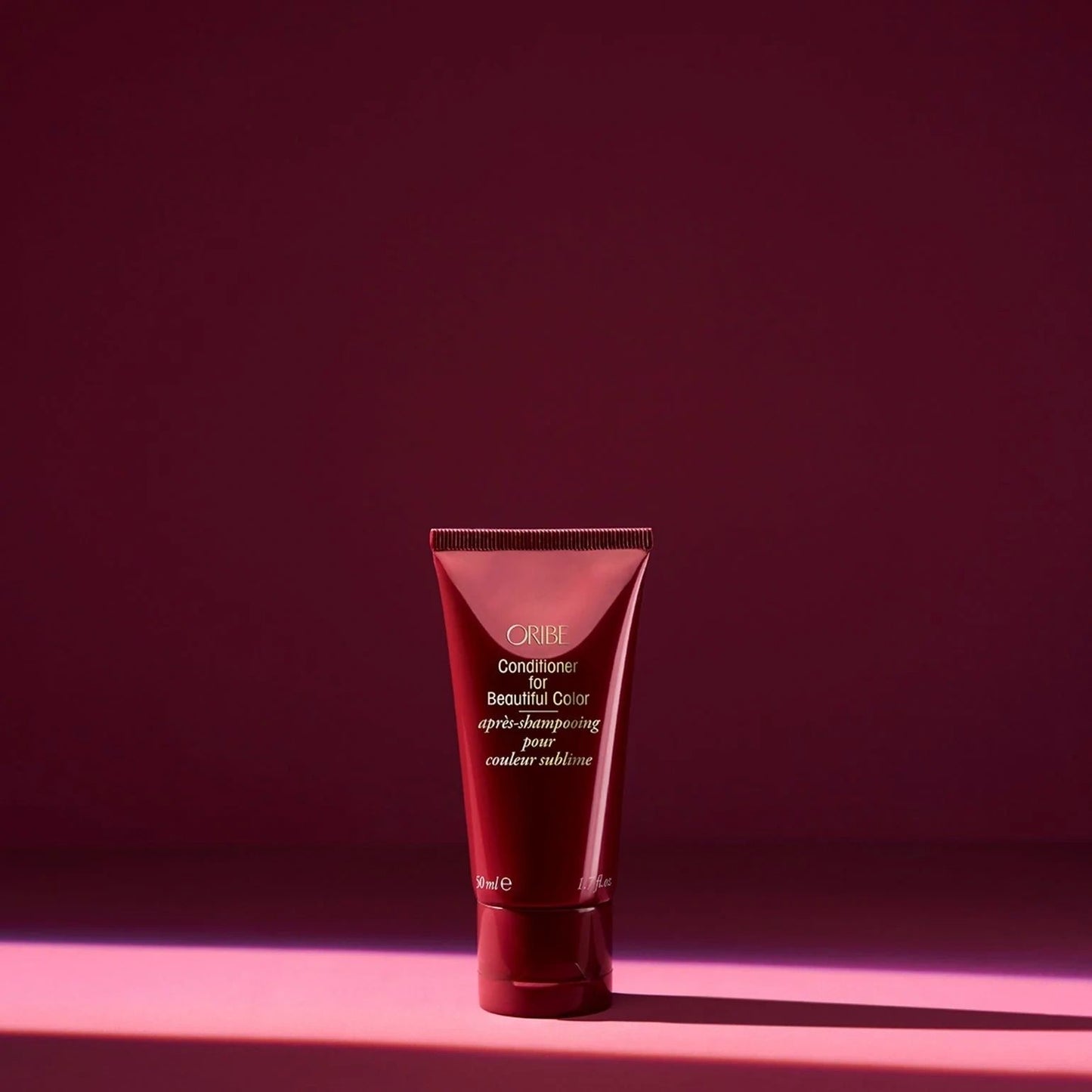 Oribe color conditioner travel tube on red background for smoothing and preserving color-treated hair