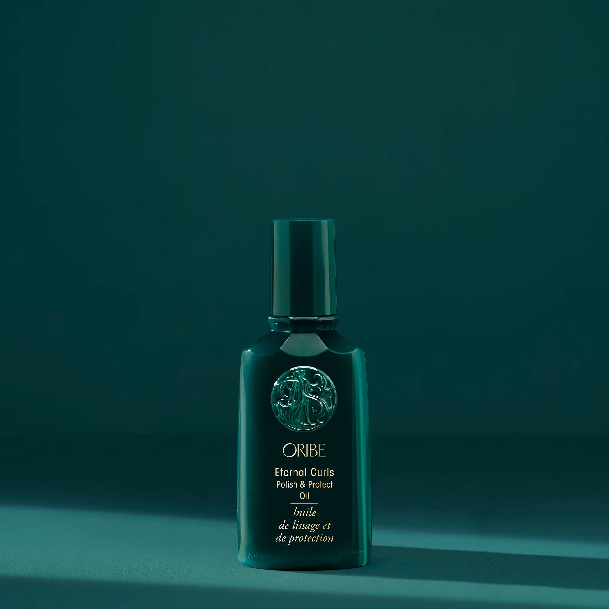 Oribe Eternal Curls Polish & Protect Oil bottle on a teal background