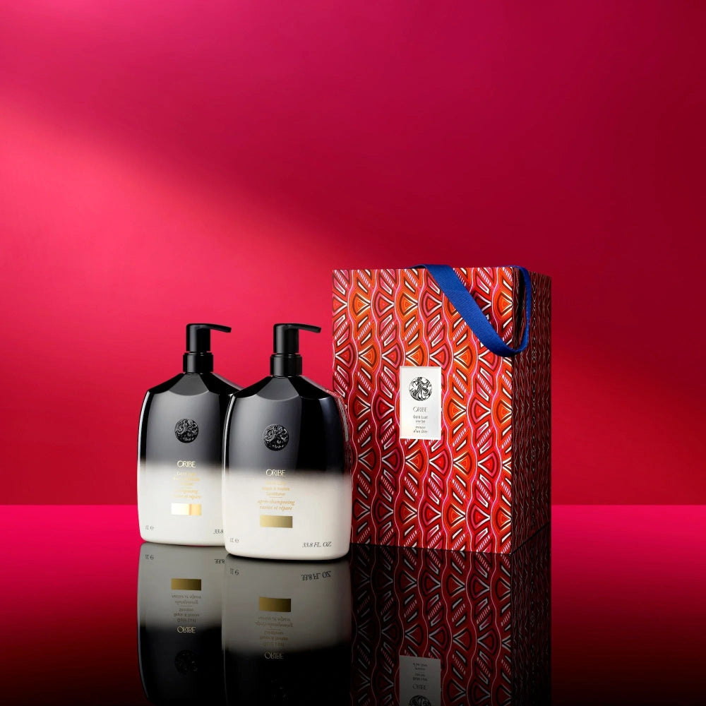 Oribe Gold Lust liter shampoo and conditioner displayed beside limited-edition patterned gift box on red background