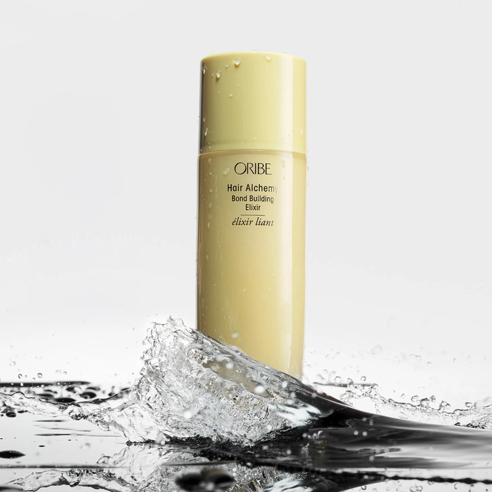 Oribe Hair Alchemy Bond Building Elixir with water splash representing lightweight formula and deep penetration