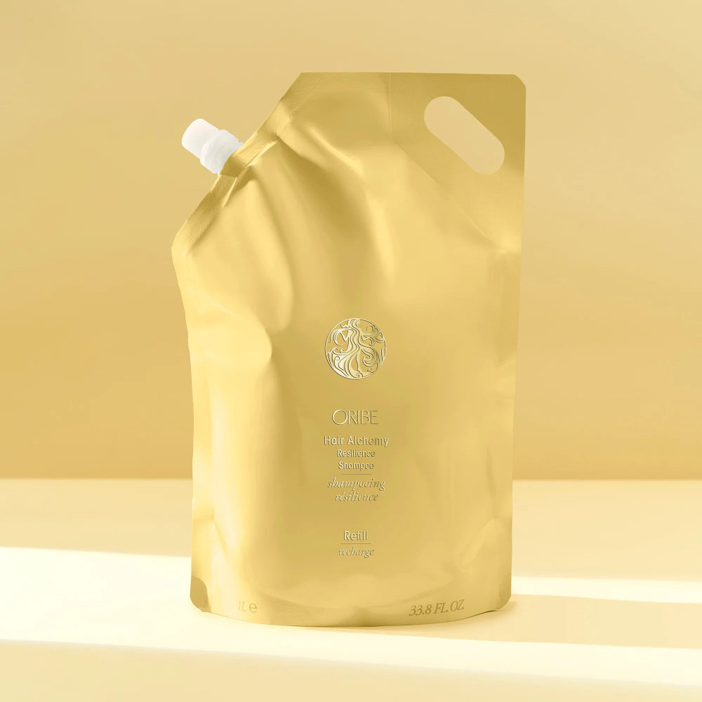 Oribe Hair Alchemy Shampoo liter refill bag on a yellow background