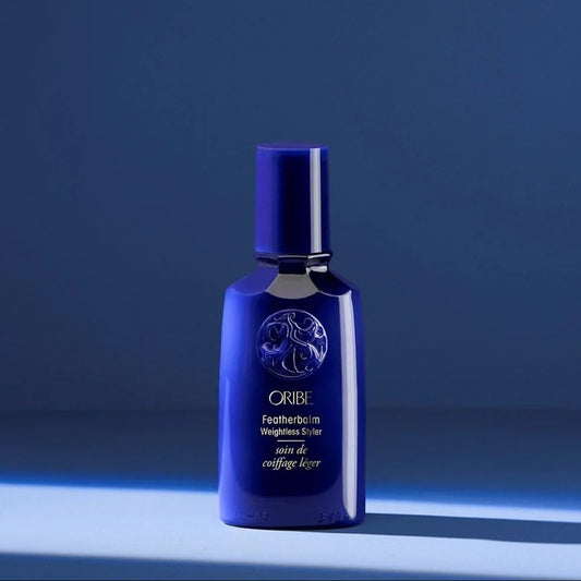 Oribe Featherbalm Weightless Styler in blue bottle for lightweight styling, softness, and natural movement