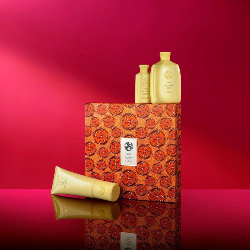 Oribe Hair Alchemy gift set displayed against red background with Thandiwe Muriu limited-edition packaging