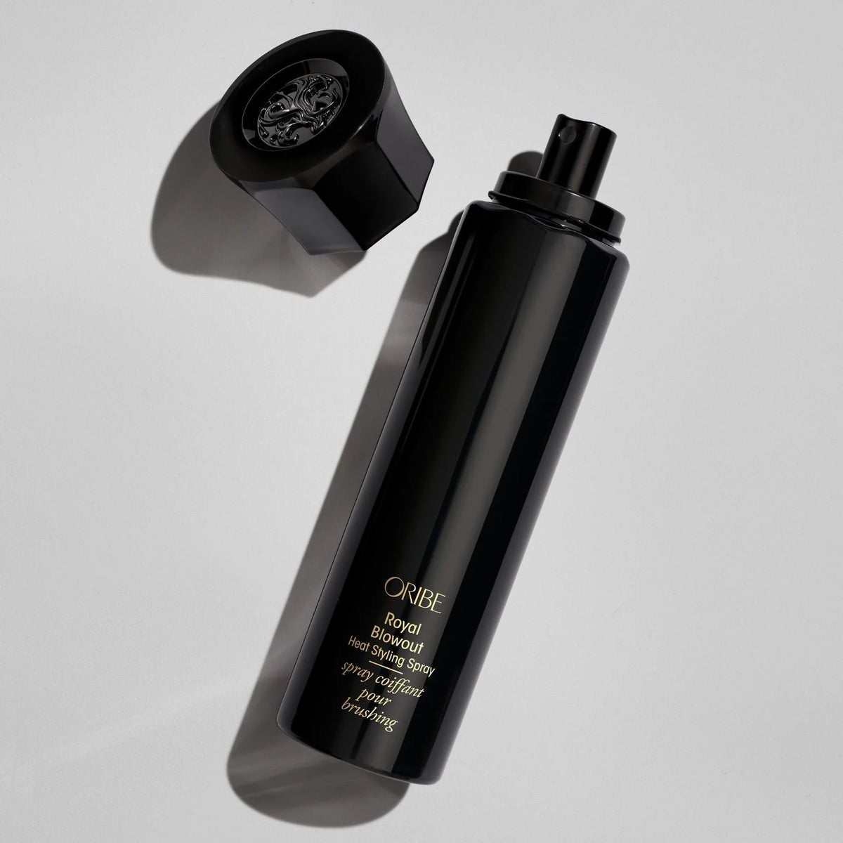 Oribe Royal Blowout Heat Styling Spray black bottle with cap removed, revealing the spray applicator for heat styling and blowouts.