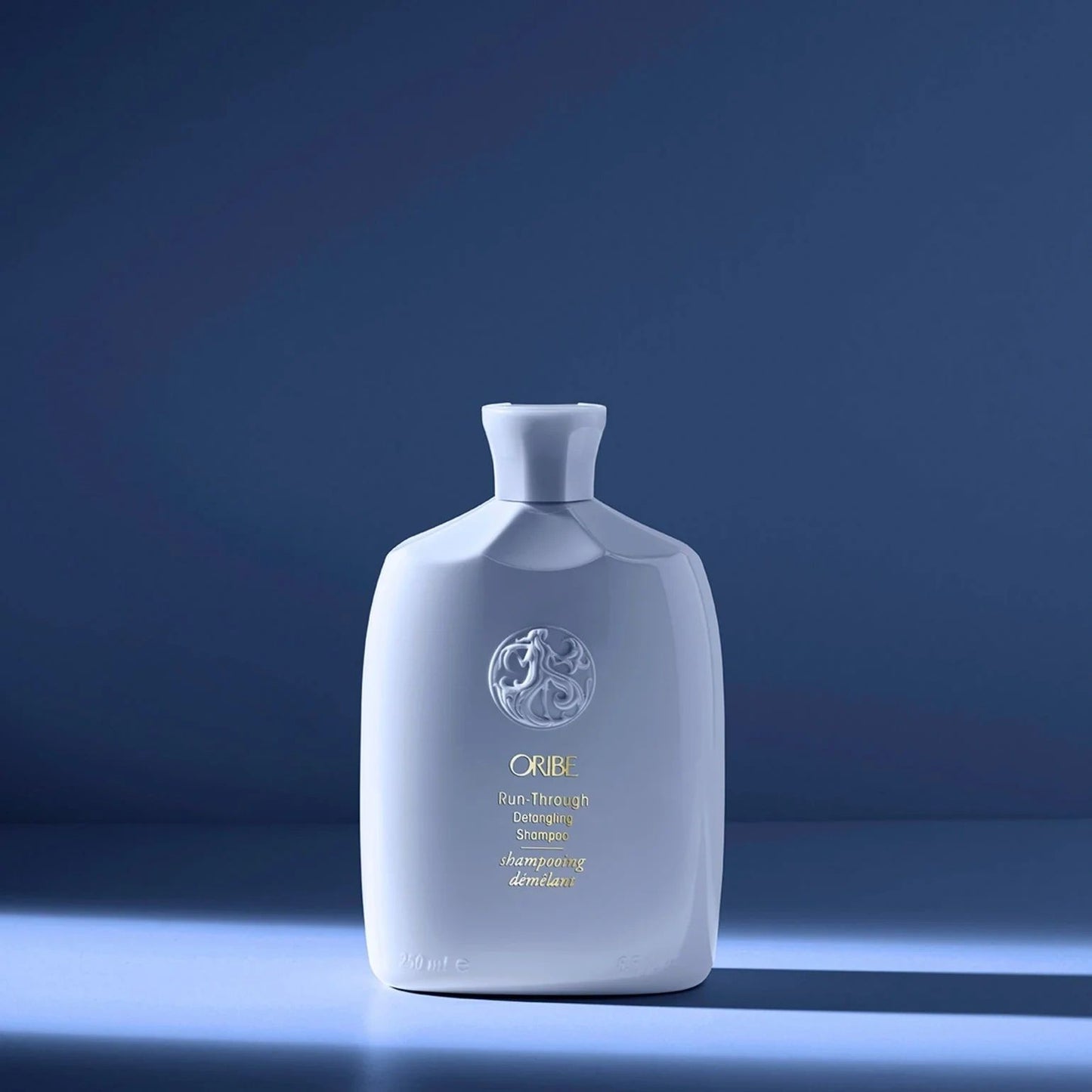 Oribe Run-Through Detangling Shampoo in light blue bottle for gentle cleansing and easy detangling