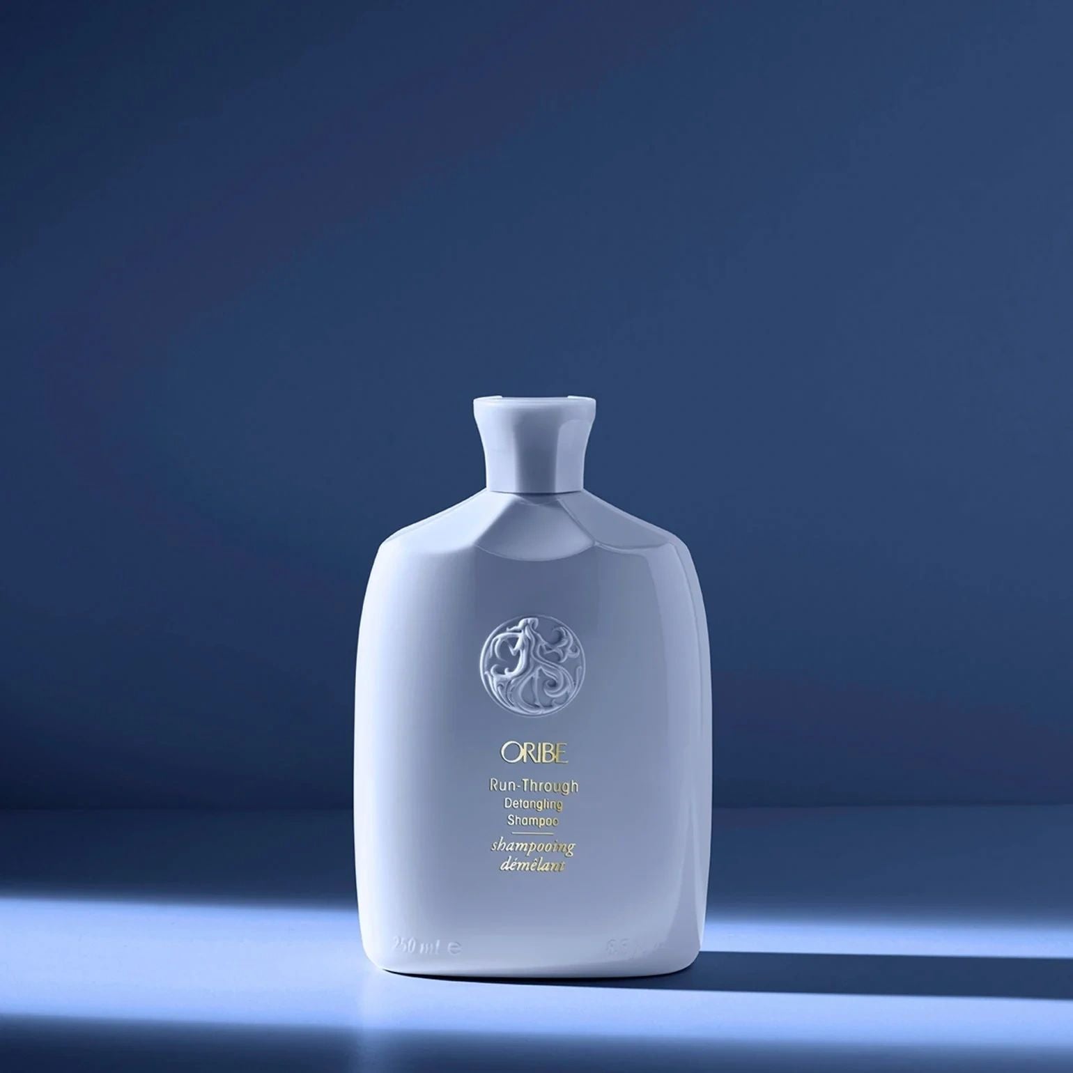 Oribe Run-Through Detangling Shampoo in light blue bottle for gentle cleansing and easy detangling