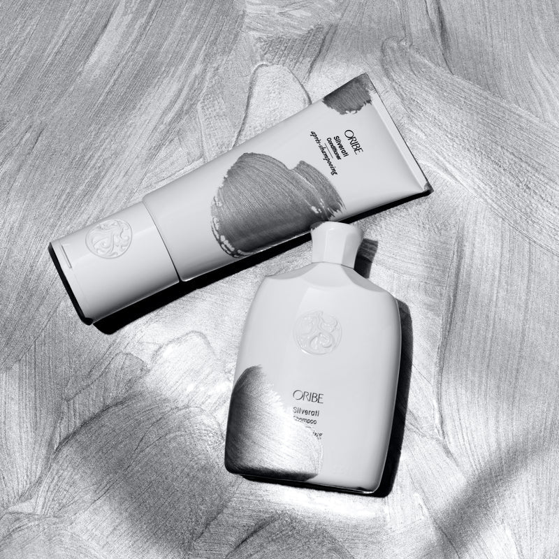 Oribe Silverati Shampoo and Conditioner on a silver brushed background