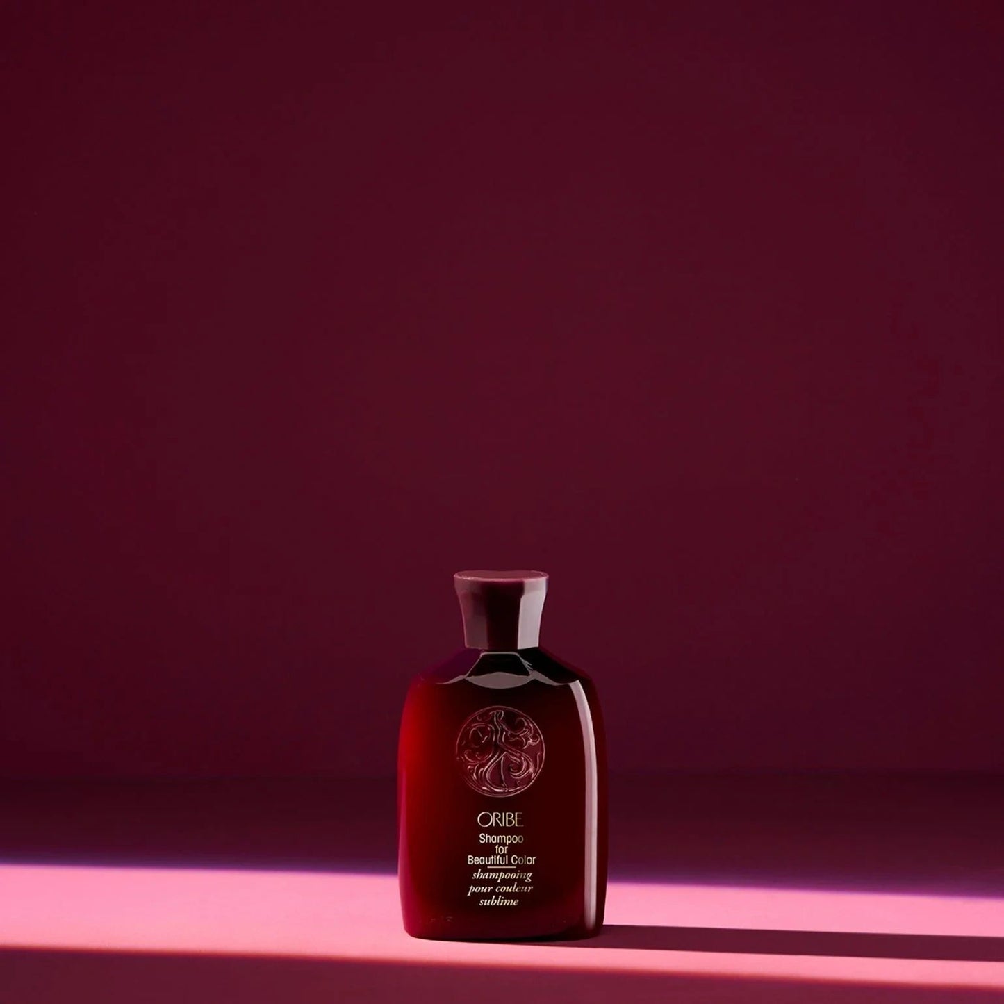 Oribe color shampoo travel size bottle on red background for preserving vibrant hair color and preventing fade