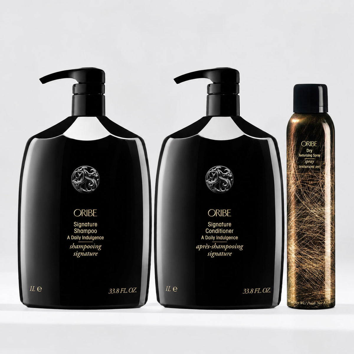 Oribe Signature Shampoo and Conditioner 1-liter bottles with Dry Texturizing Spray, a luxury hair care set for cleansing, conditioning, volume, and texture.