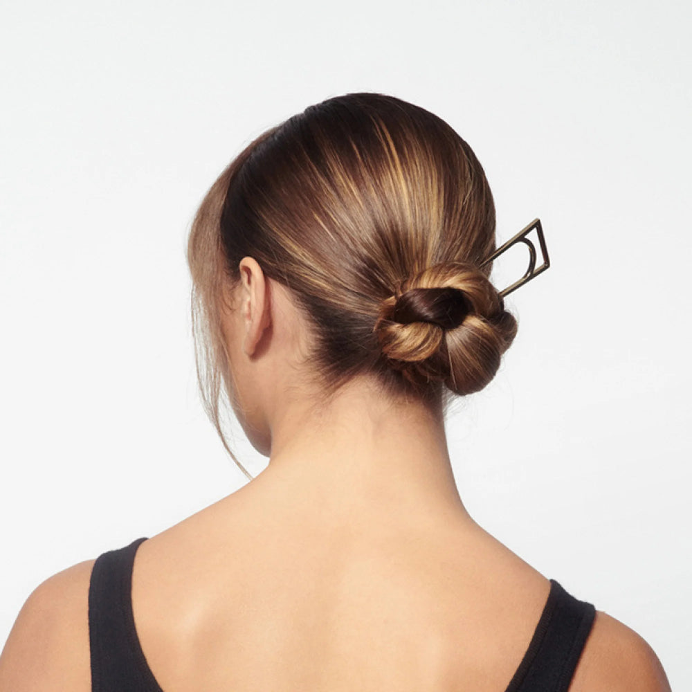 Sleek low bun styled with Oribe Superfine Hair Spray for smooth polished hold