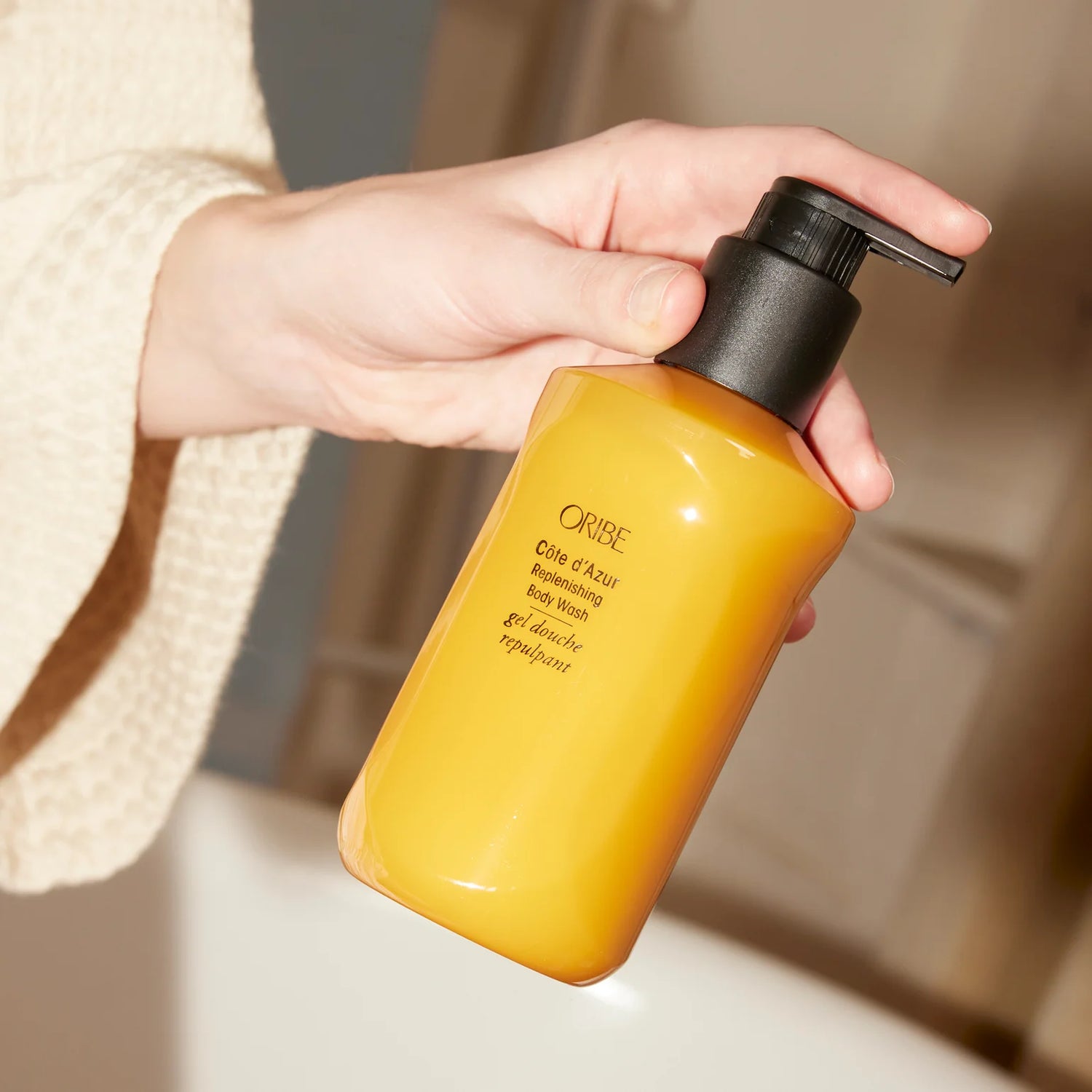 holding Oribe Côte d’Azur replenishing body wash bottle for hydrating cleansing