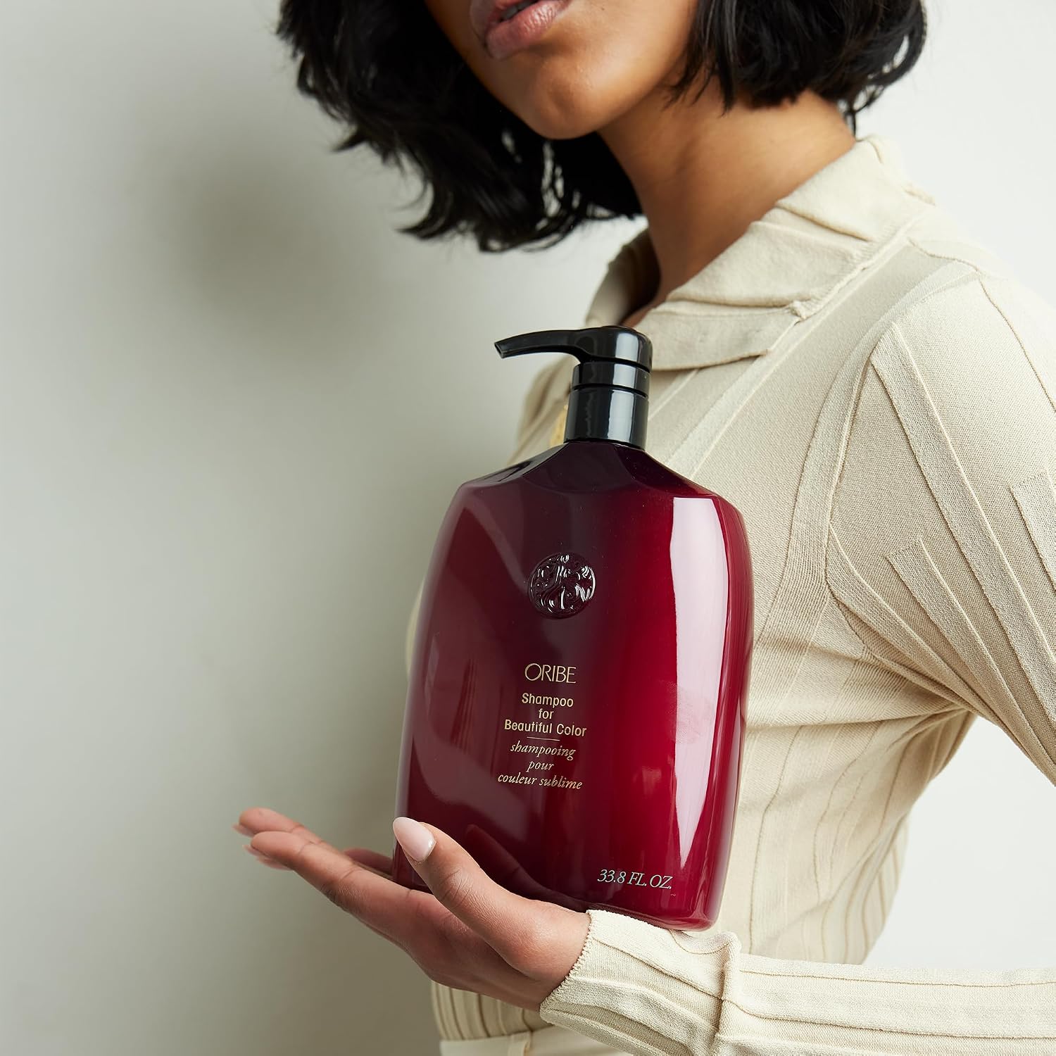 Woman holding a liter bottle of Oribe color care shampoo 