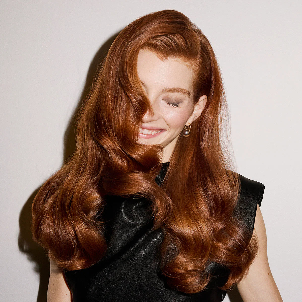 Woman with long, wavy red hair that is smooth and shiny from Oribe Anti-Frizz products