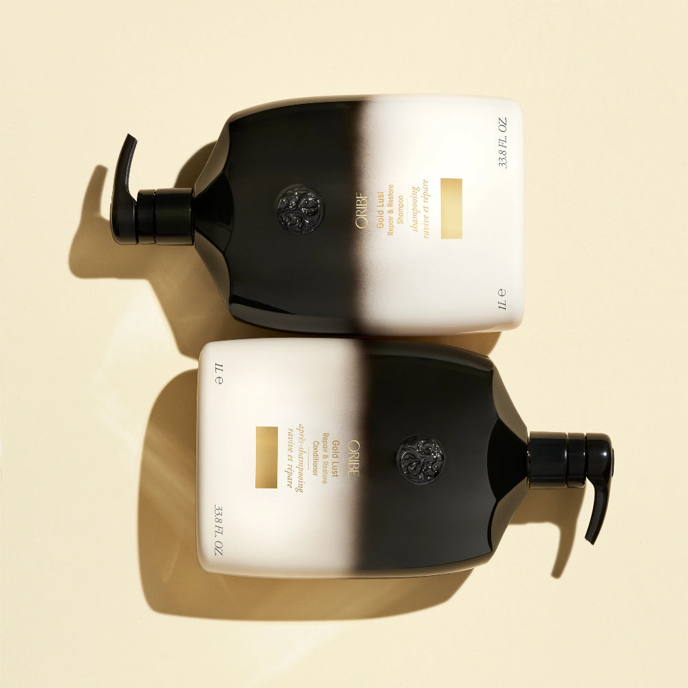 Oribe Gold Lust 33.8 oz liter shampoo and conditioner bottles laid flat on neutral background
