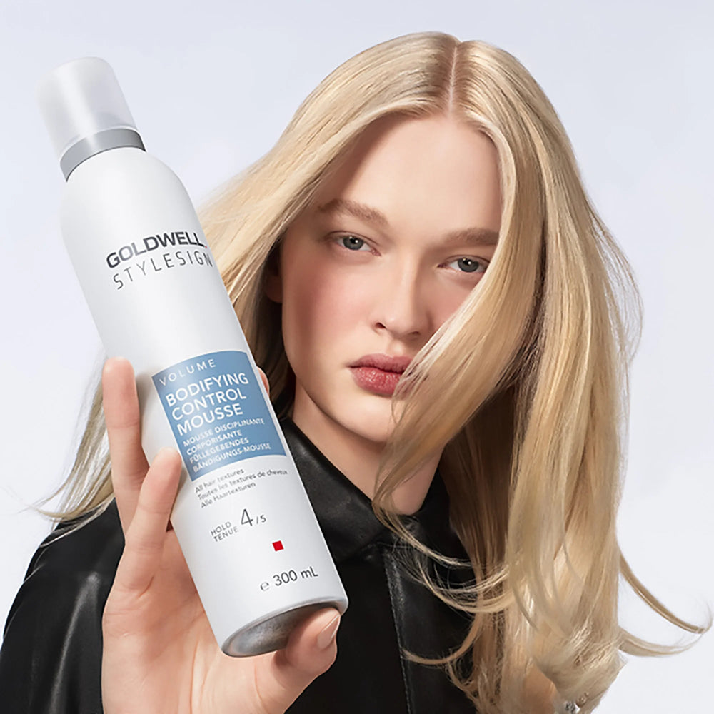 Model holding Goldwell StyleSign Bodifying Control Mousse for lightweight volume, body, and flexible styling control