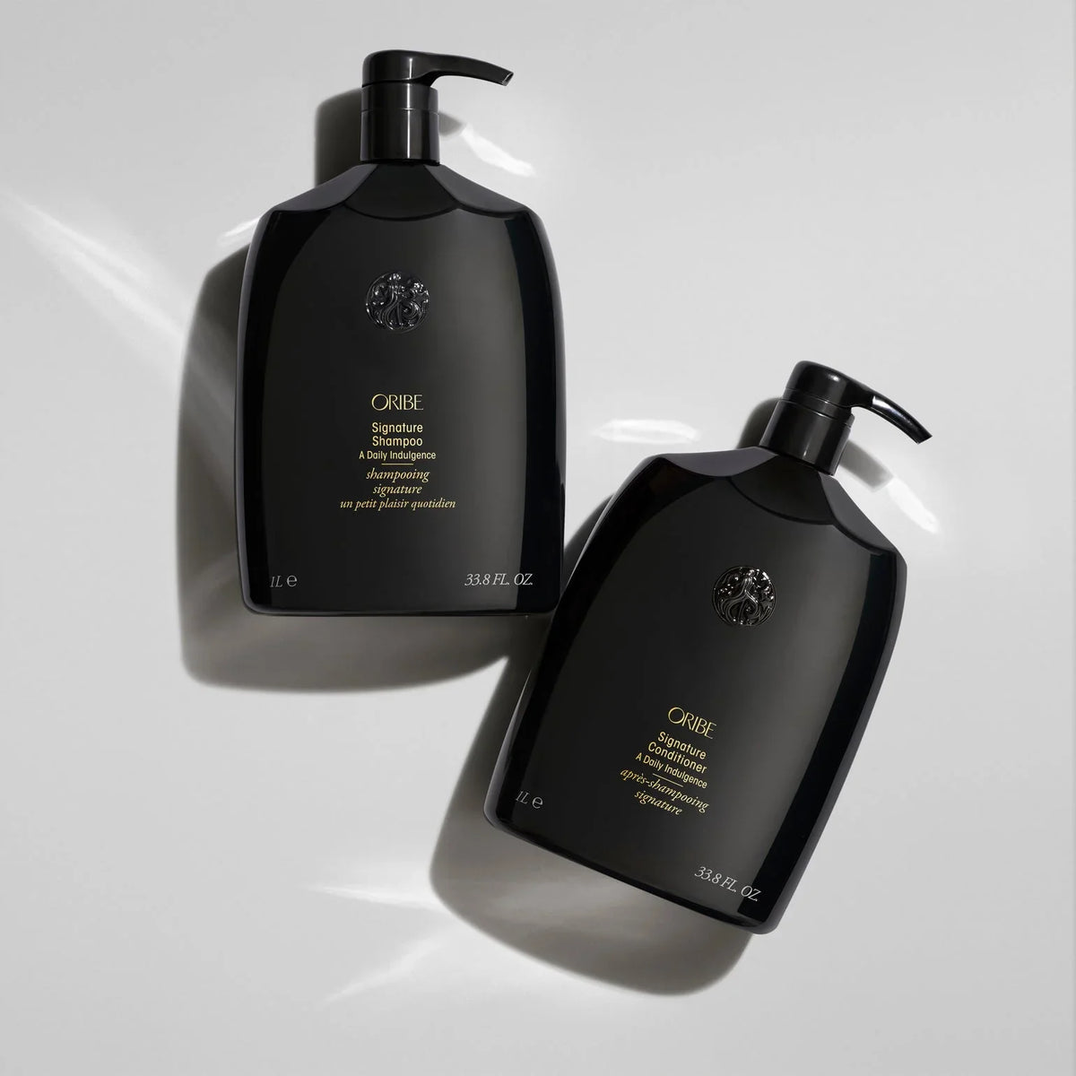 Oribe Signature Shampoo and Conditioner 1-liter black pump bottles displayed together on a light background, luxury daily hair care for cleansing and hydration.