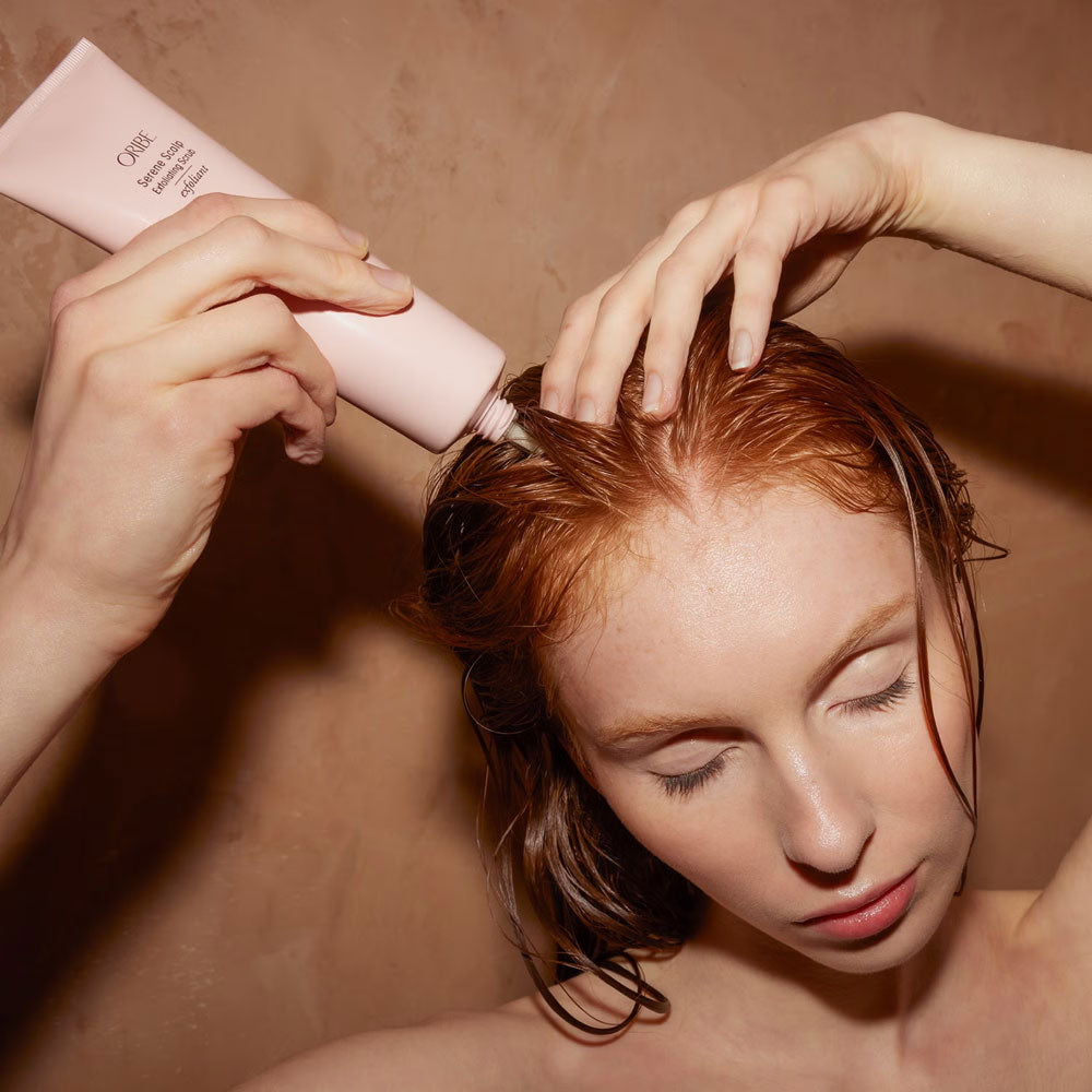 applying Oribe Serene Scalp exfoliating scrub to remove buildup and cleanse the scalp