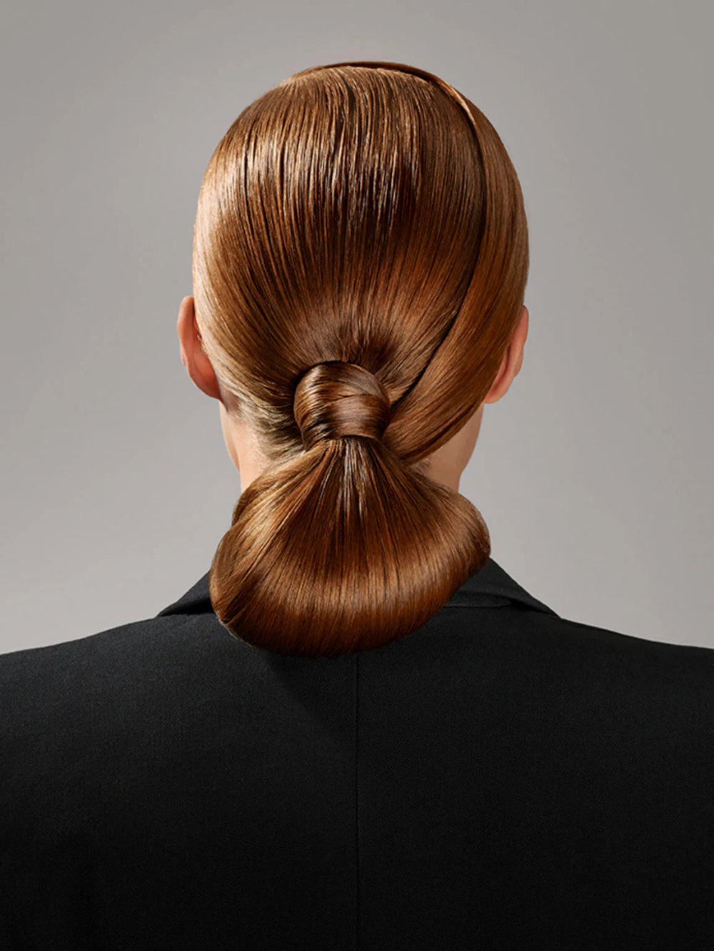 Sleek bun hairstyle secured with Oribe Superfine Strong hairspray for all-day hold