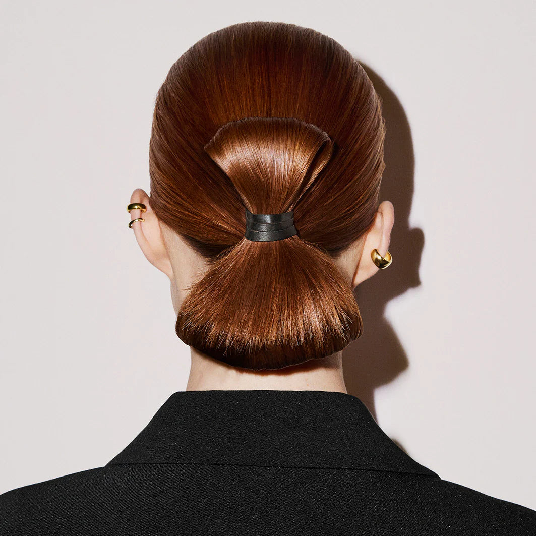 Polished sleek bun styled with Oribe Supershine Wax Stick for flyaway control and shine
