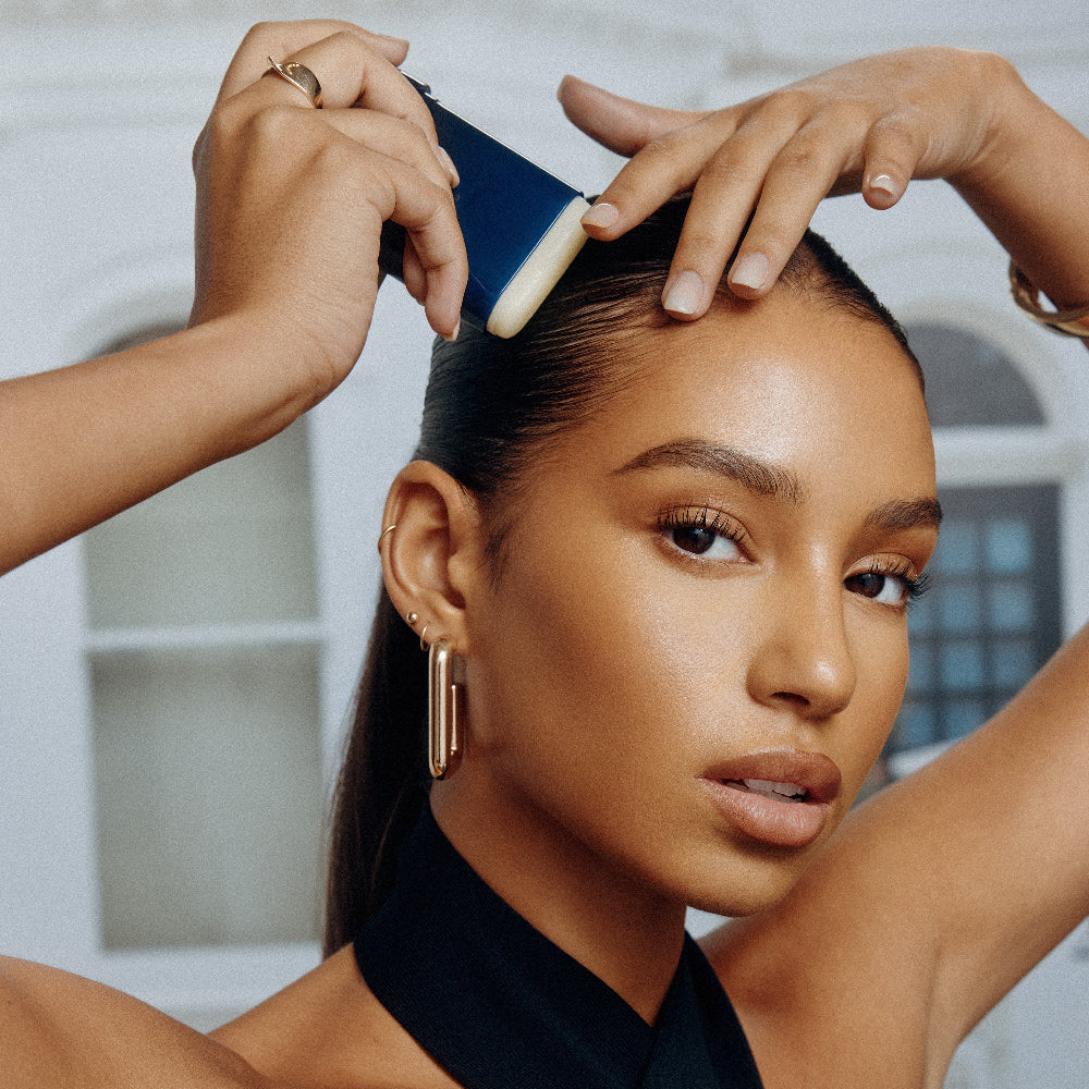 Applying Oribe Supershine Wax Stick to smooth edges and control flyaways