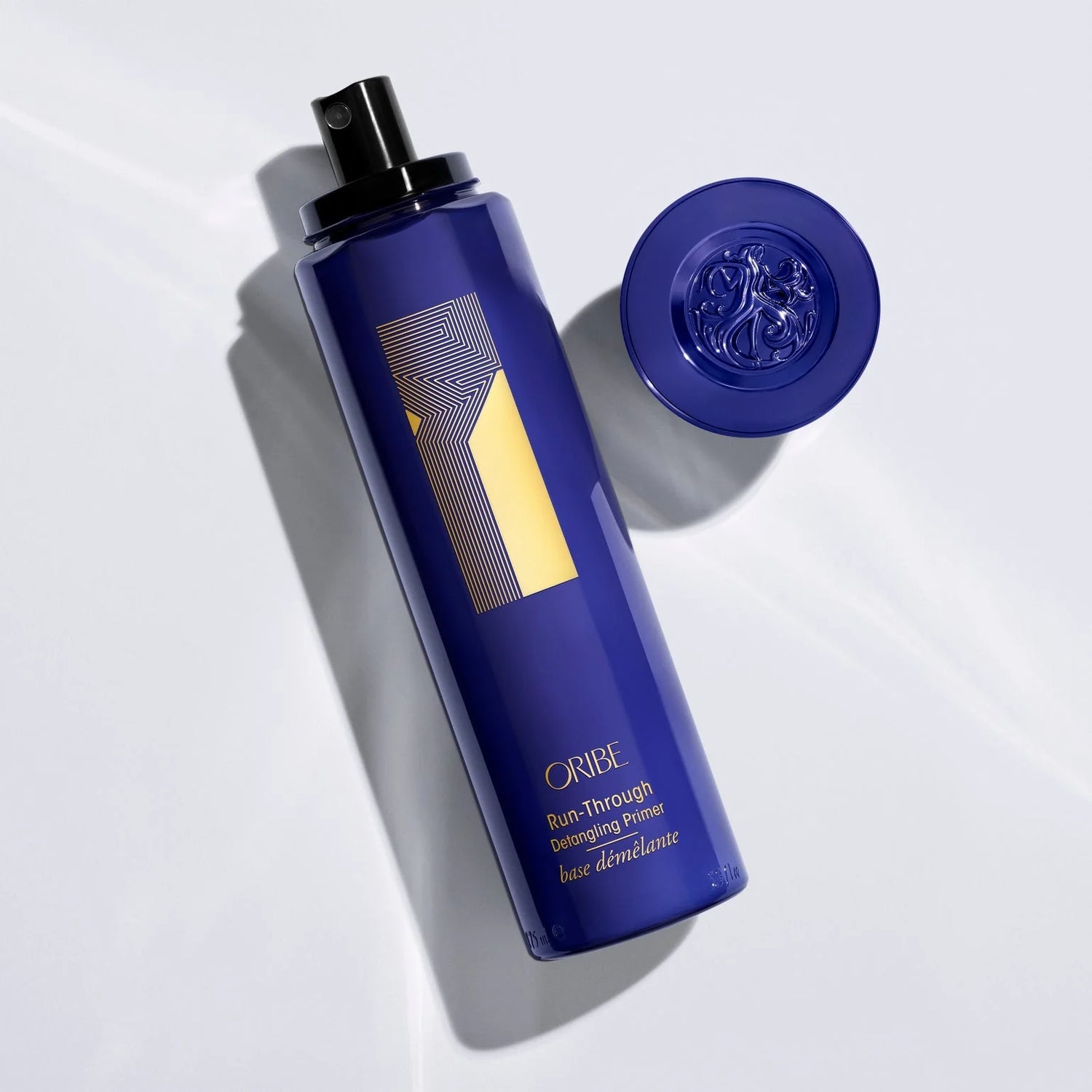 Oribe Run-Through Detangling Spray bottle with cap removed showing lightweight leave-in formula